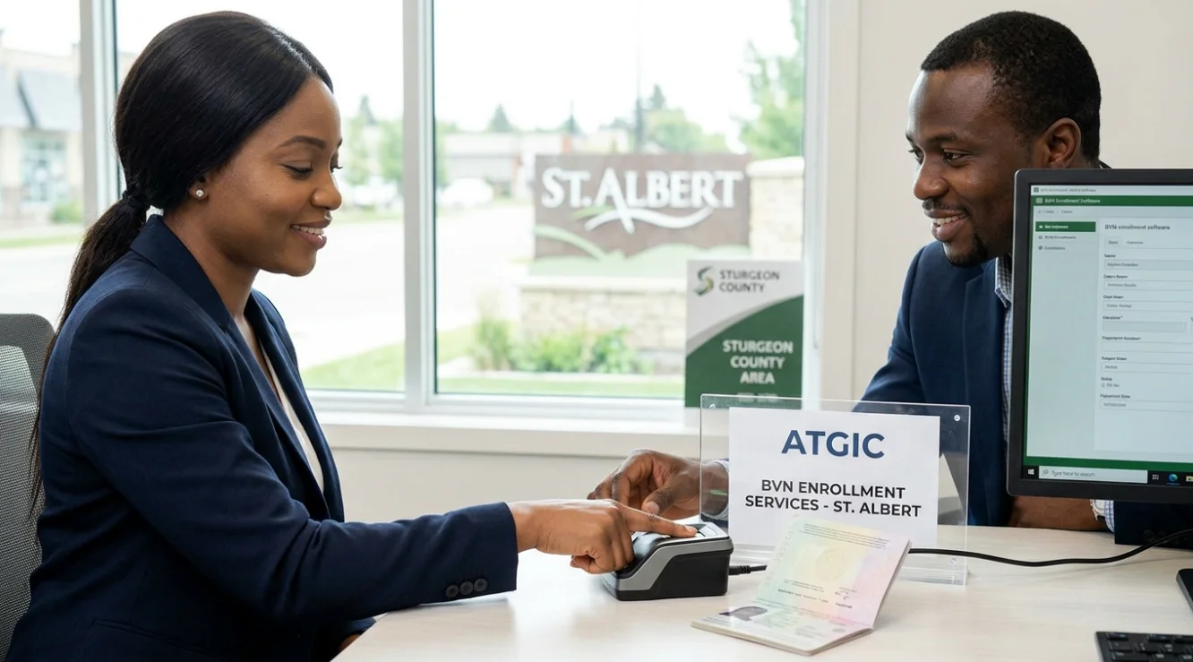 A woman completing her BVN enrolment at the ATGIC office in St. Albert, placing her finger on a biometric scanner while a consultant manages the registration software in front of a window overlooking the St. Albert and Sturgeon County area.